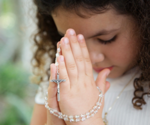 Child praying with a rosary